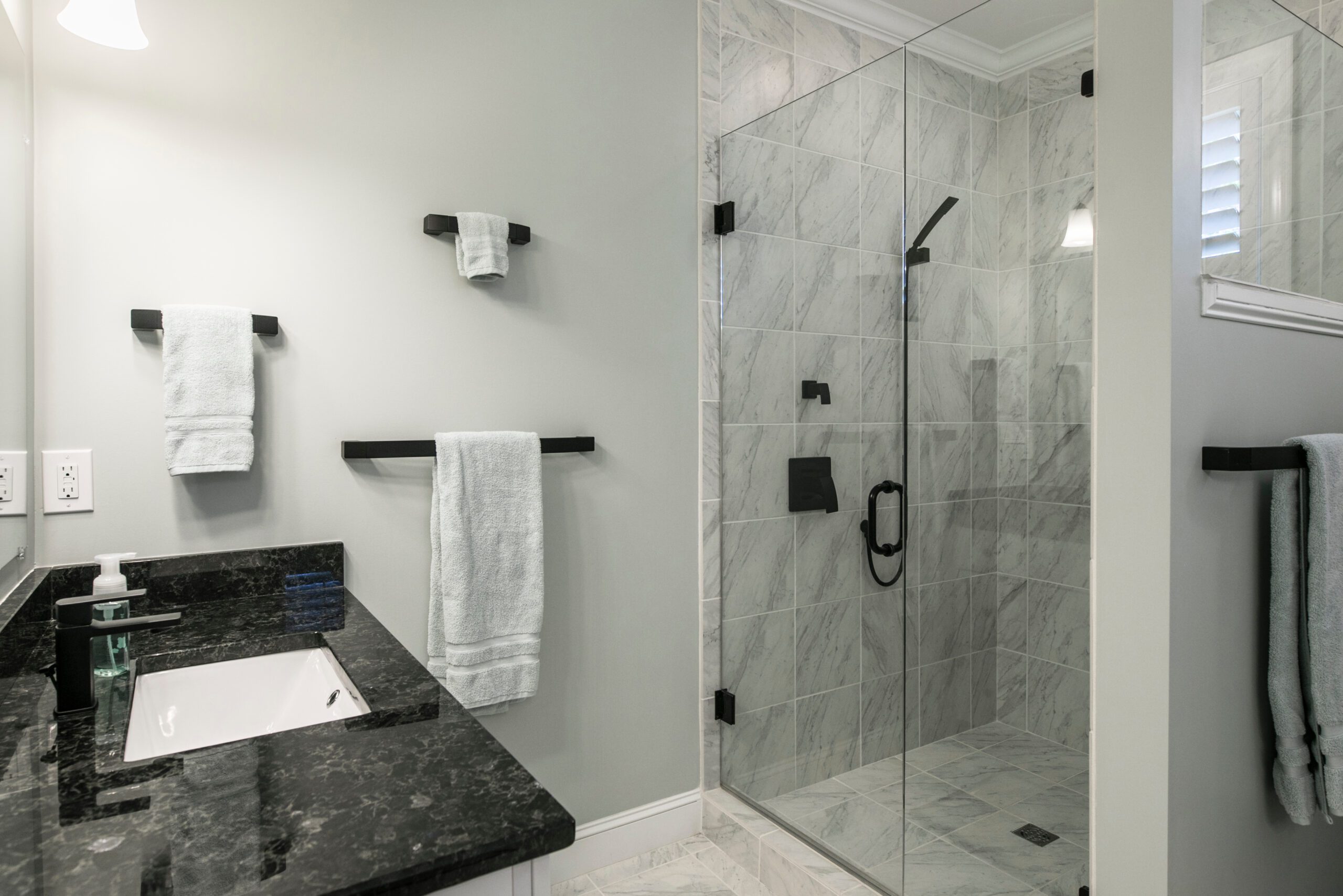 There is a small shower with a seamless glass shower door enclosure